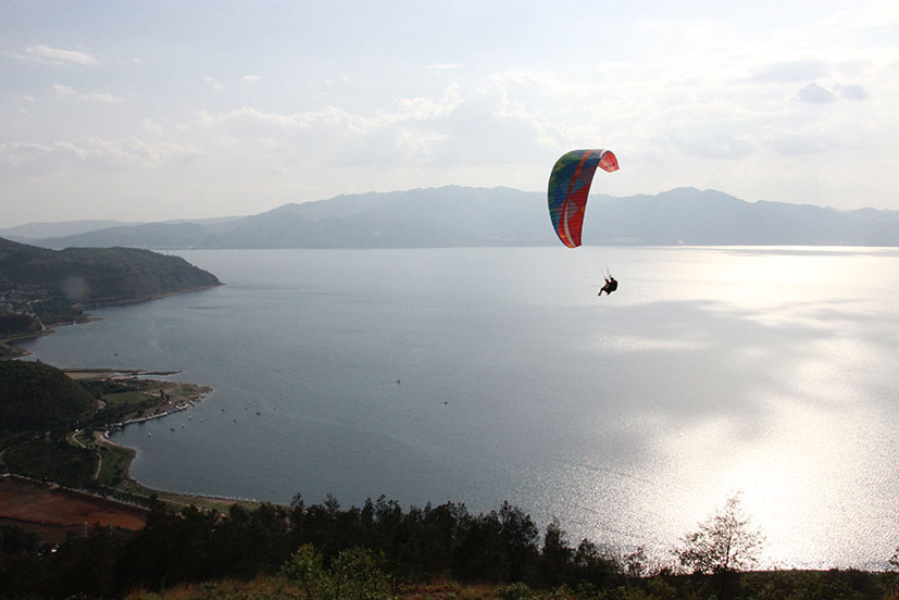 在云南竹园滑翔仙湖湾飞行营地，游客从高高的山顶乘风起飞，拥抱蓝天，俯瞰抚仙湖碧波荡漾。