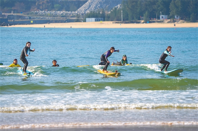 三亚后海，游客踩着冲浪板滑行。记者 袁琛 摄