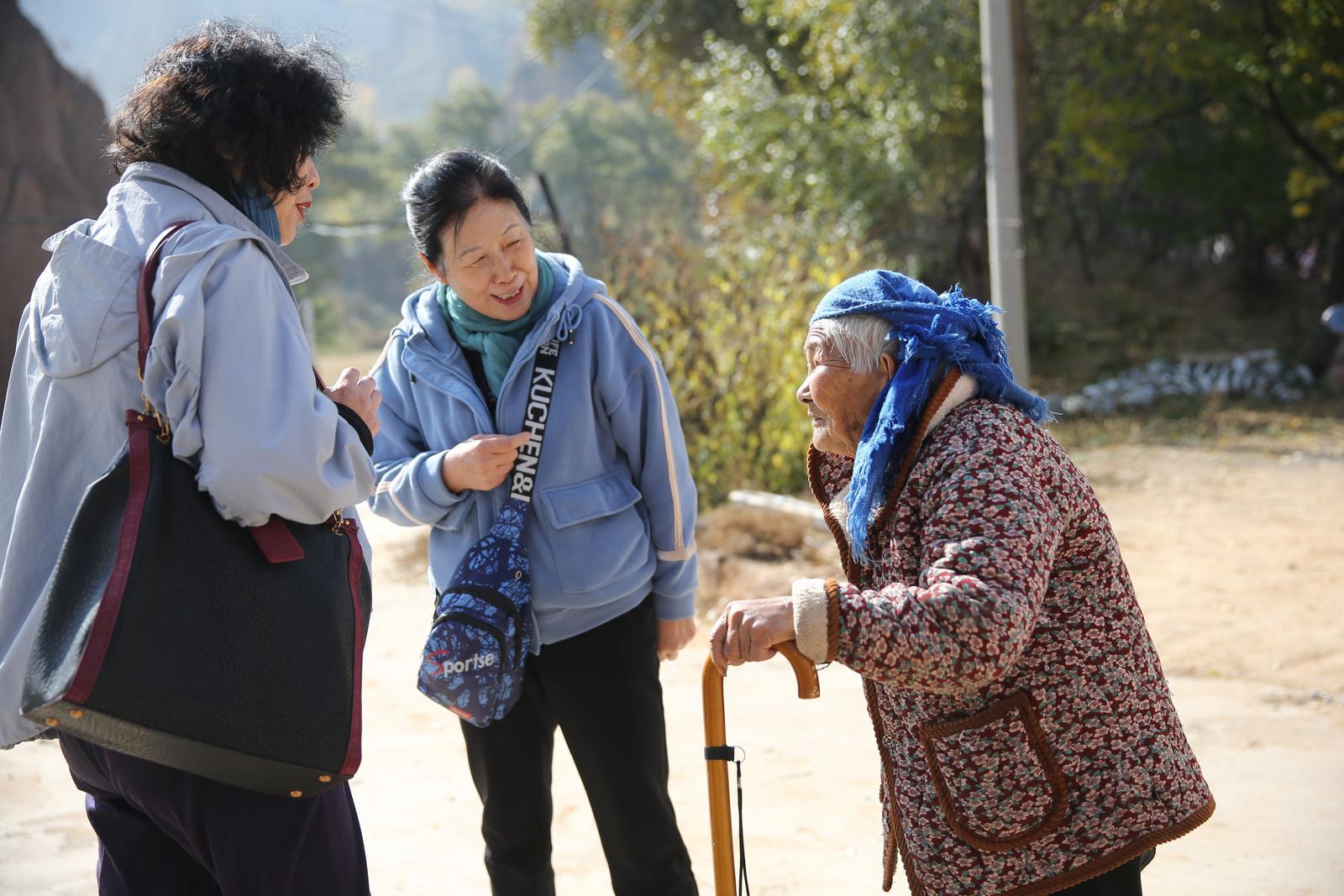 寨底古村老大娘，笑迎城里远来客。