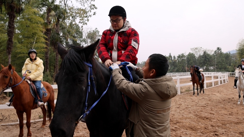 吴水良帮助游客体验骑马