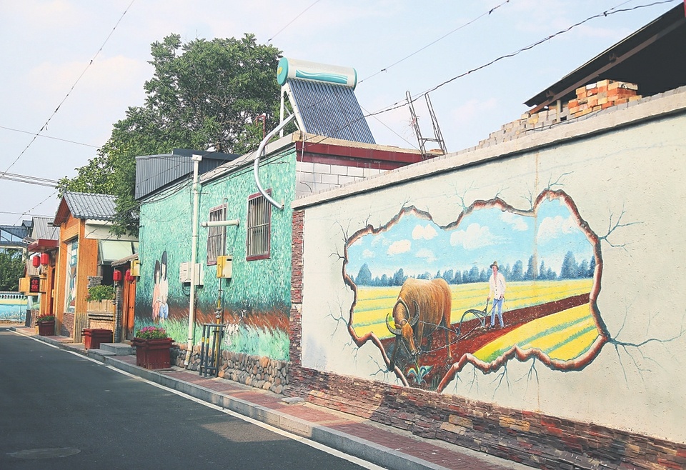 在刘家堡村，沿路建筑物墙面上的彩绘无声“诉说”着村庄的发展变化。（资料图片）